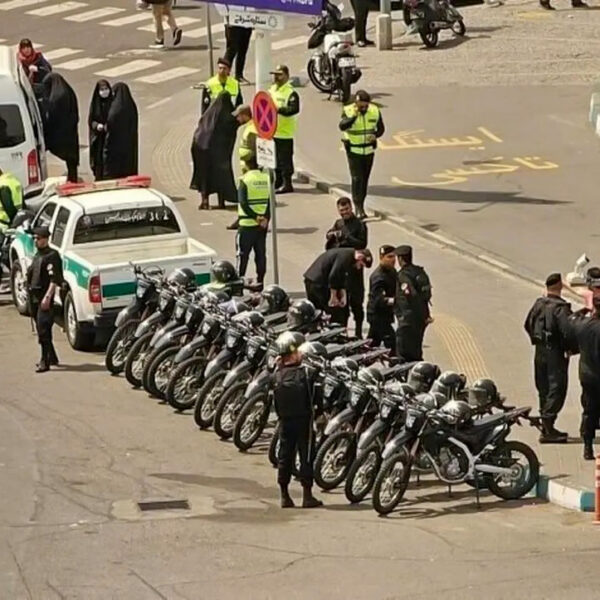 Forze di sicurezza iraniane dispiegate con macchine, moto e van per attuare posti di blocco.