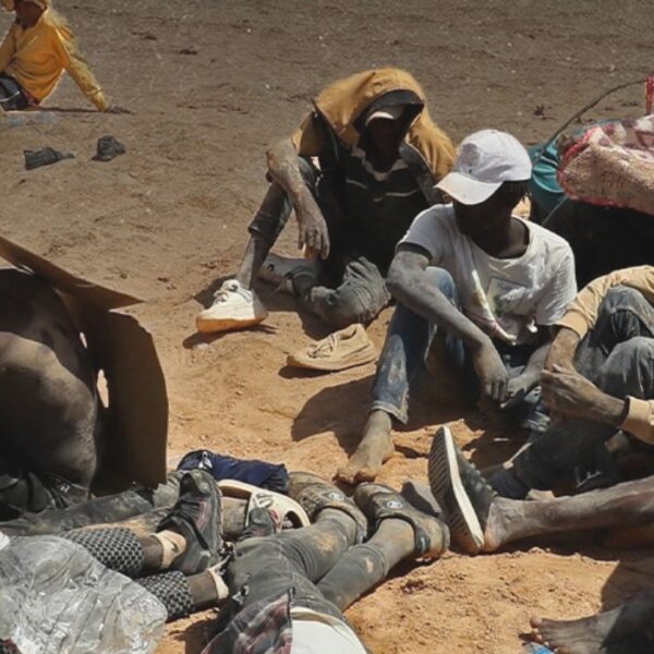 Migranti provenienti da paesi dell'Africa subsahariana, che affermano di essere stati abbandonati nel deserto dalle autorità tunisine senza acqua né riparo, siedono in una zona disabitata vicino alla città di confine di Al-Assah in Libia il 16 luglio 2023.