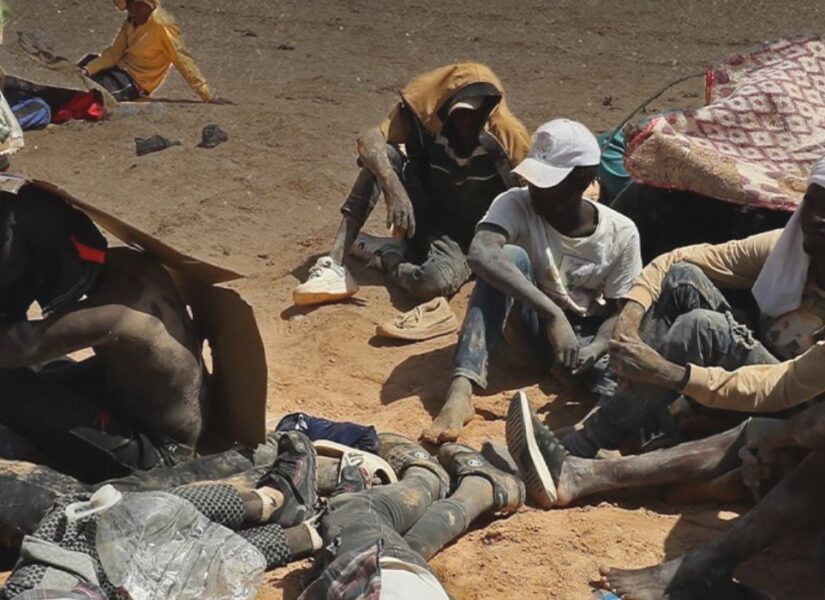 Migranti provenienti da paesi dell'Africa subsahariana, che affermano di essere stati abbandonati nel deserto dalle autorità tunisine senza acqua né riparo, siedono in una zona disabitata vicino alla città di confine di Al-Assah in Libia il 16 luglio 2023.