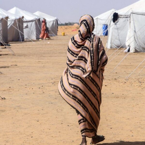 Una donna sudanese di spalle fuggita da El-Fasher cammina tra le tende di un campo per sfollati nella città settentrionale di Al-Dabba, il 13 novembre 2025.