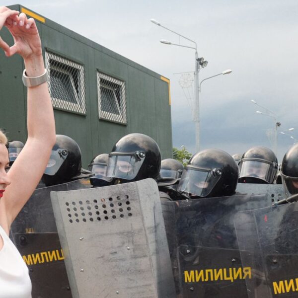 Maryia kalesnikava davanti a dei poliziotti schierati che fa il simbolo del cuore con le mani. Foto scattata nel 2020.