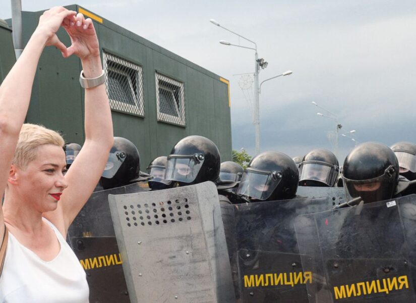Maryia kalesnikava davanti a dei poliziotti schierati che fa il simbolo del cuore con le mani. Foto scattata nel 2020.