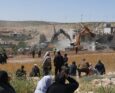 Il 4 maggio 2026, nel villaggio di al-Dirat, vicino alla città di Yatta, nella Cisgiordania occupata, alcuni palestinesi osservano le forze di sicurezza israeliane mentre gli escavatori demoliscono una casa palestinese costruita senza permesso.
