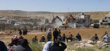 Il 4 maggio 2026, nel villaggio di al-Dirat, vicino alla città di Yatta, nella Cisgiordania occupata, alcuni palestinesi osservano le forze di sicurezza israeliane mentre gli escavatori demoliscono una casa palestinese costruita senza permesso.