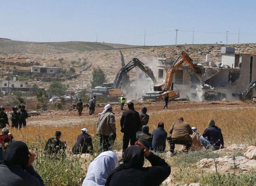 Il 4 maggio 2026, nel villaggio di al-Dirat, vicino alla città di Yatta, nella Cisgiordania occupata, alcuni palestinesi osservano le forze di sicurezza israeliane mentre gli escavatori demoliscono una casa palestinese costruita senza permesso.