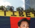 Dorji Dolma, una donna tibetana, protesta davanti a una bandiera del Tibet libero a Statue Square, Hong Kong, il 27 giugno, con l'imponente edificio della Bank of China sullo sfondo.