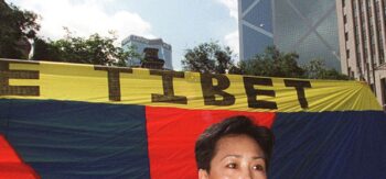 Dorji Dolma, una donna tibetana, protesta davanti a una bandiera del Tibet libero a Statue Square, Hong Kong, il 27 giugno, con l'imponente edificio della Bank of China sullo sfondo.