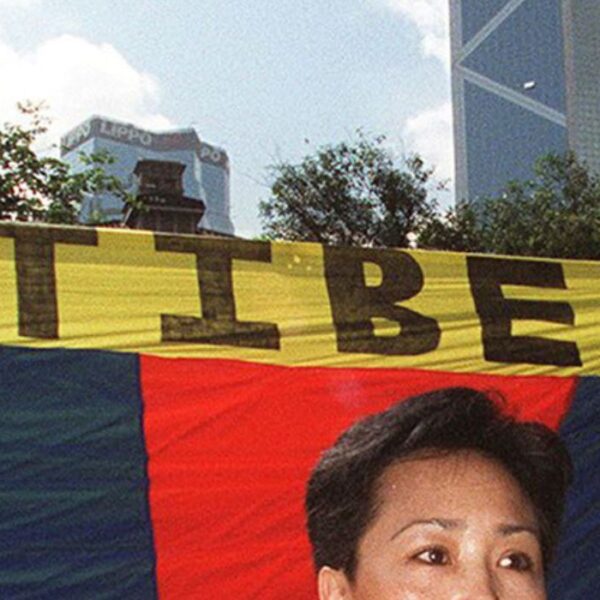 Dorji Dolma, una donna tibetana, protesta davanti a una bandiera del Tibet libero a Statue Square, Hong Kong, il 27 giugno, con l'imponente edificio della Bank of China sullo sfondo.