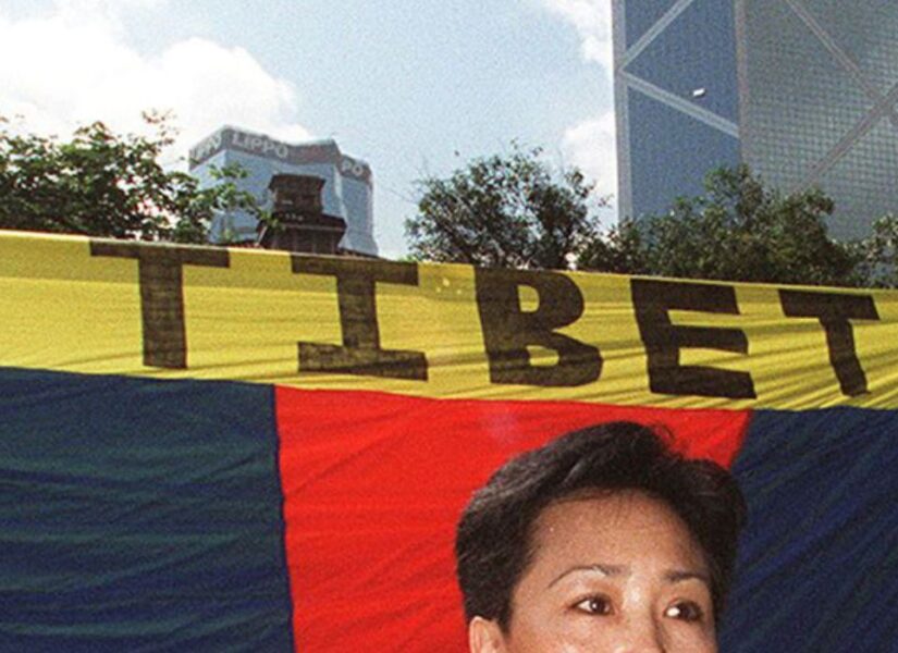 Dorji Dolma, una donna tibetana, protesta davanti a una bandiera del Tibet libero a Statue Square, Hong Kong, il 27 giugno, con l'imponente edificio della Bank of China sullo sfondo.