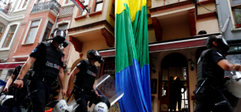 Turchia repressione della comunità lgbtqia+. Nell'immagine: forze di polizia sfilano davanti a una bandiera lgbtqia+