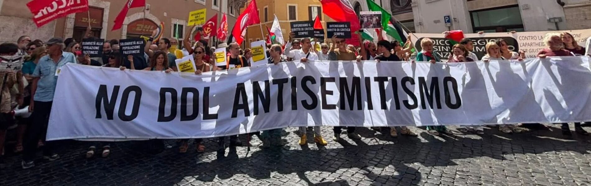 Striscione "No ddl antisemitismo" bianco con scritta nera.